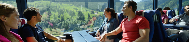 A group of friends looking out the panoramic window of a Golden Pass train 